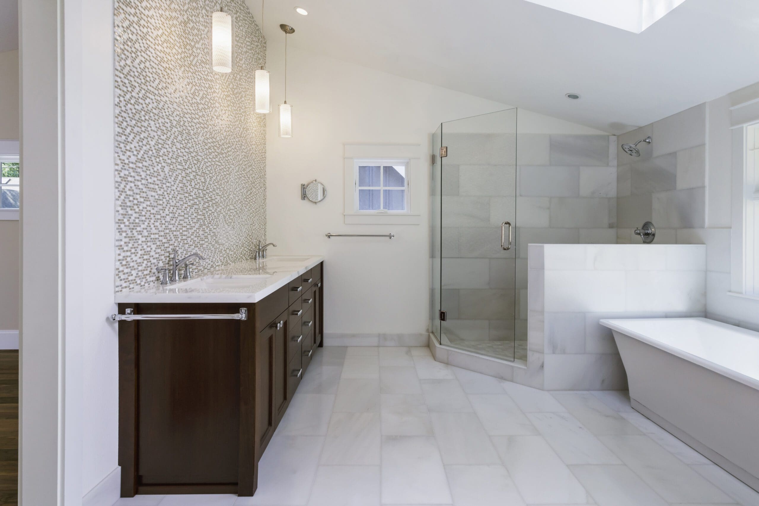 Interior view of a bathroom with double sinks, walk in shower, and modern bathtub.